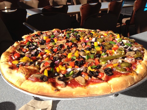 vegan pizza with olives, mushrooms, bell peppers, and jalapeños on top, but no cheese
