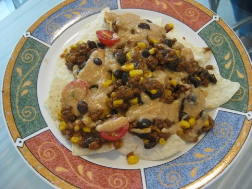 nachos covered with beans, corn, tomatoes, and vegan cheese