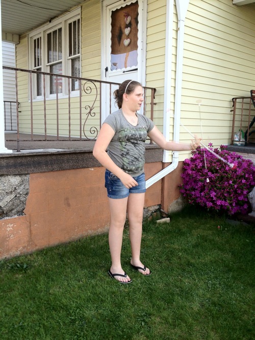 girl standing in front yard twirling baton